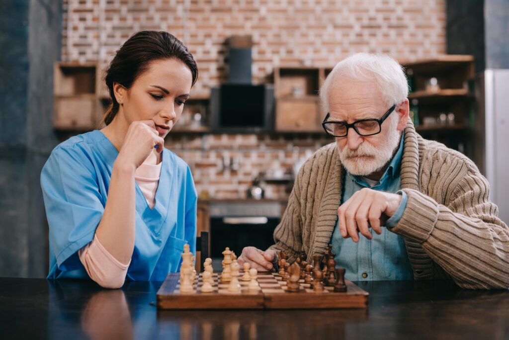 Old man and female caregiver playing chess