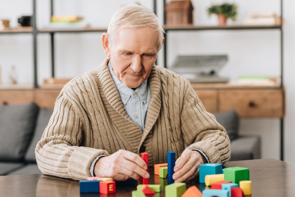 senior man playing with wooden toys at home
