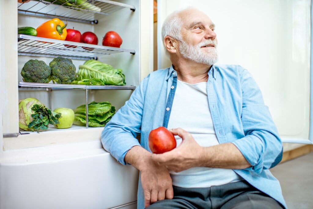 Senior man with healthy products in refrigerator